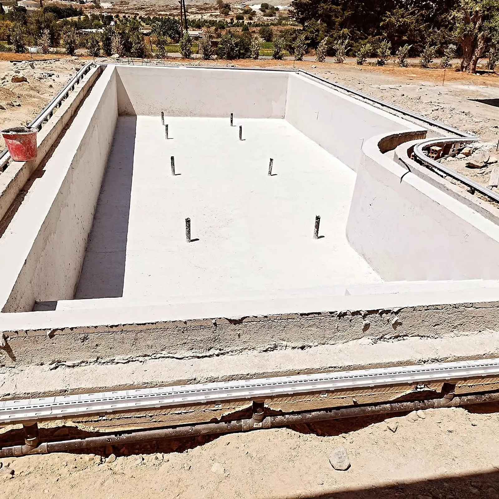 Rendered white pool shell with pipe connections ready for tiling
